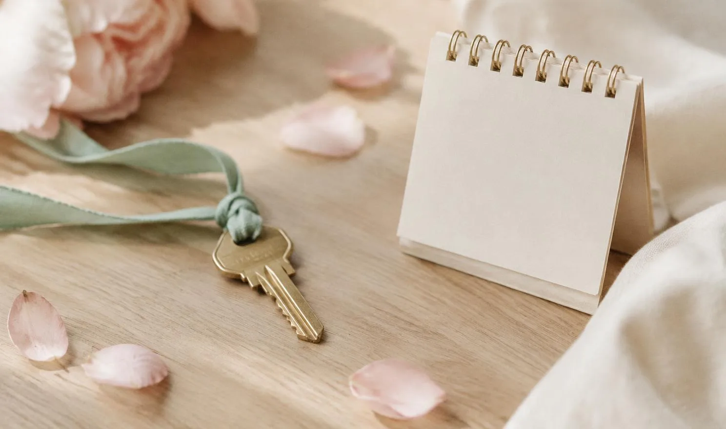 Brass house key on a mint ribbon beside a small paper desk calendar
