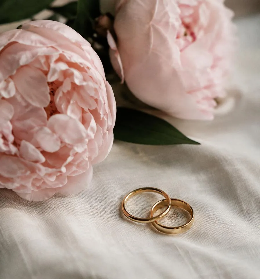 Two rings on ivory linen beside peonies